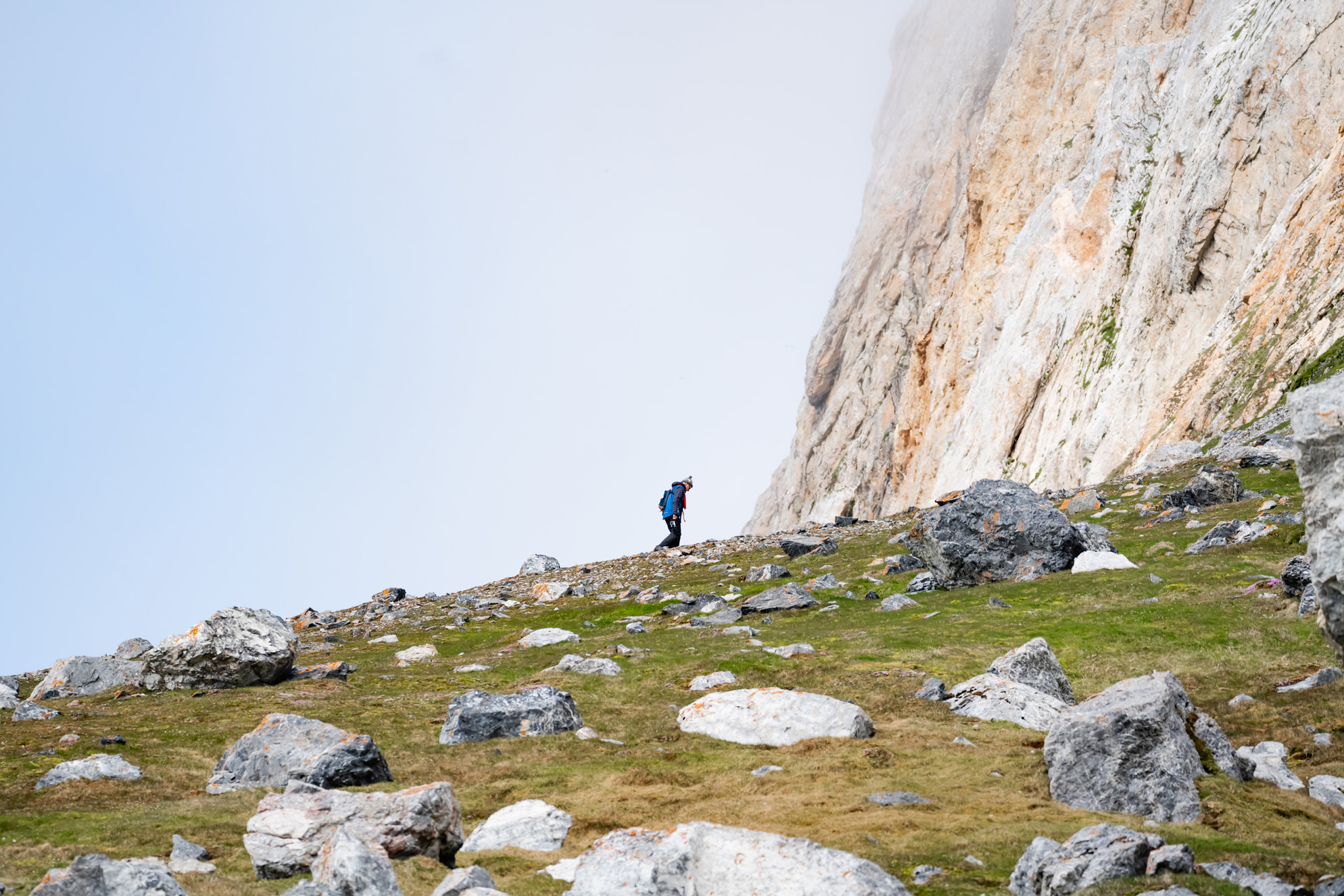 Hiker climbing a rocky ridge towards mountain, Gnalodden, Svalbard, Lina Stock @DivergentTravelers